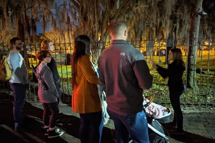 Families with a stroller listening to a guide by an iron fence on a family-friendly ghost tour in Savannah GA