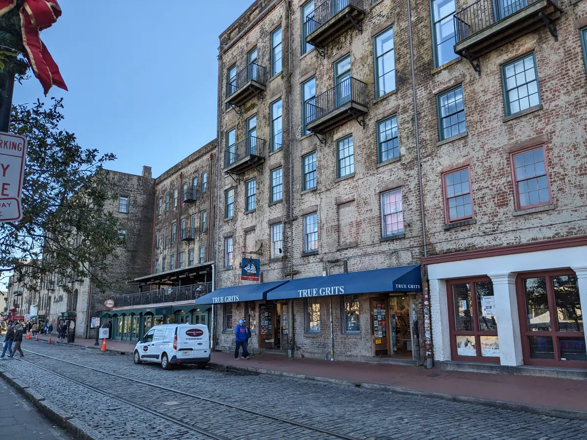 Old cotton warehouses on cobbled River Street, where the Ghosts and Gravestones Savannah GA ghost tour boards